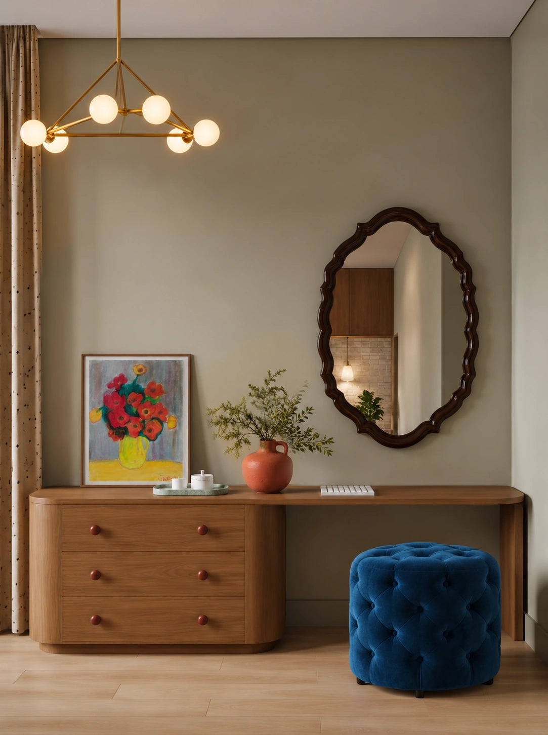 Modern entryway with a warm wood console, sculptural dark wood oval mirror, blue tufted ottoman, colorful floral artwork, ceramic vase with greenery, and a contemporary brass pendant light.