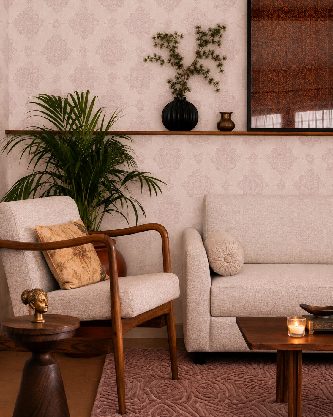 A styled interior corner featuring a cream upholstered armchair with a patterned pillow, a matching sofa, a wooden coffee table with a lit candle, a potted palm, and a wall-mounted shelf with vases against patterned wallpaper.