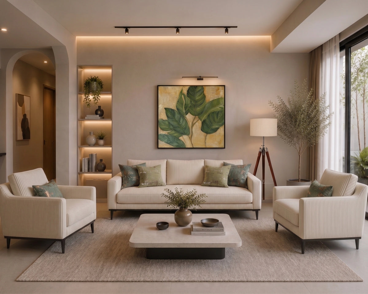 A modern living room featuring a cream-colored sofa, two matching armchairs, a low rectangular coffee table, and a large framed botanical leaf print on the wall above the sofa.