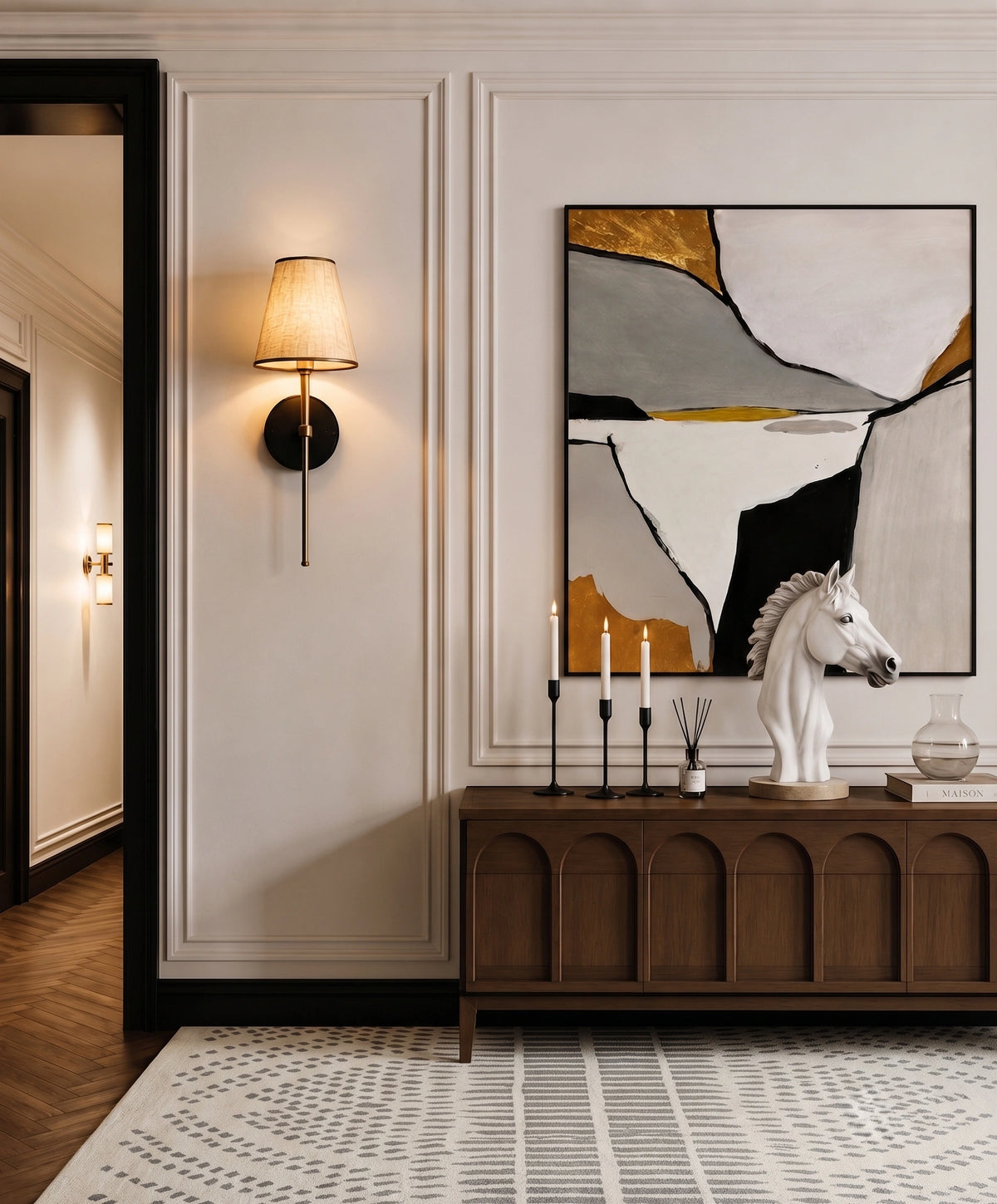 A modern abstract wall art print featuring geometric shapes in black, white, gray, and gold, styled in a contemporary hallway above a dark wood console table with a white horse bust sculpture.