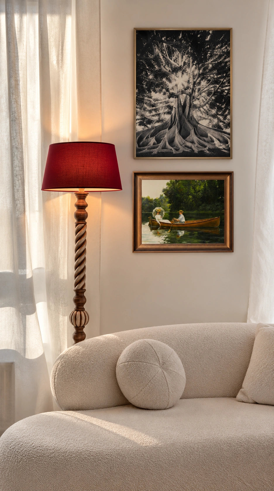 Cozy neutral living room with a cream boucle sofa, round textured cushion, sculptural wooden floor lamp with a deep red shade, vintage framed artwork, and sheer curtains illuminated by warm natural light.