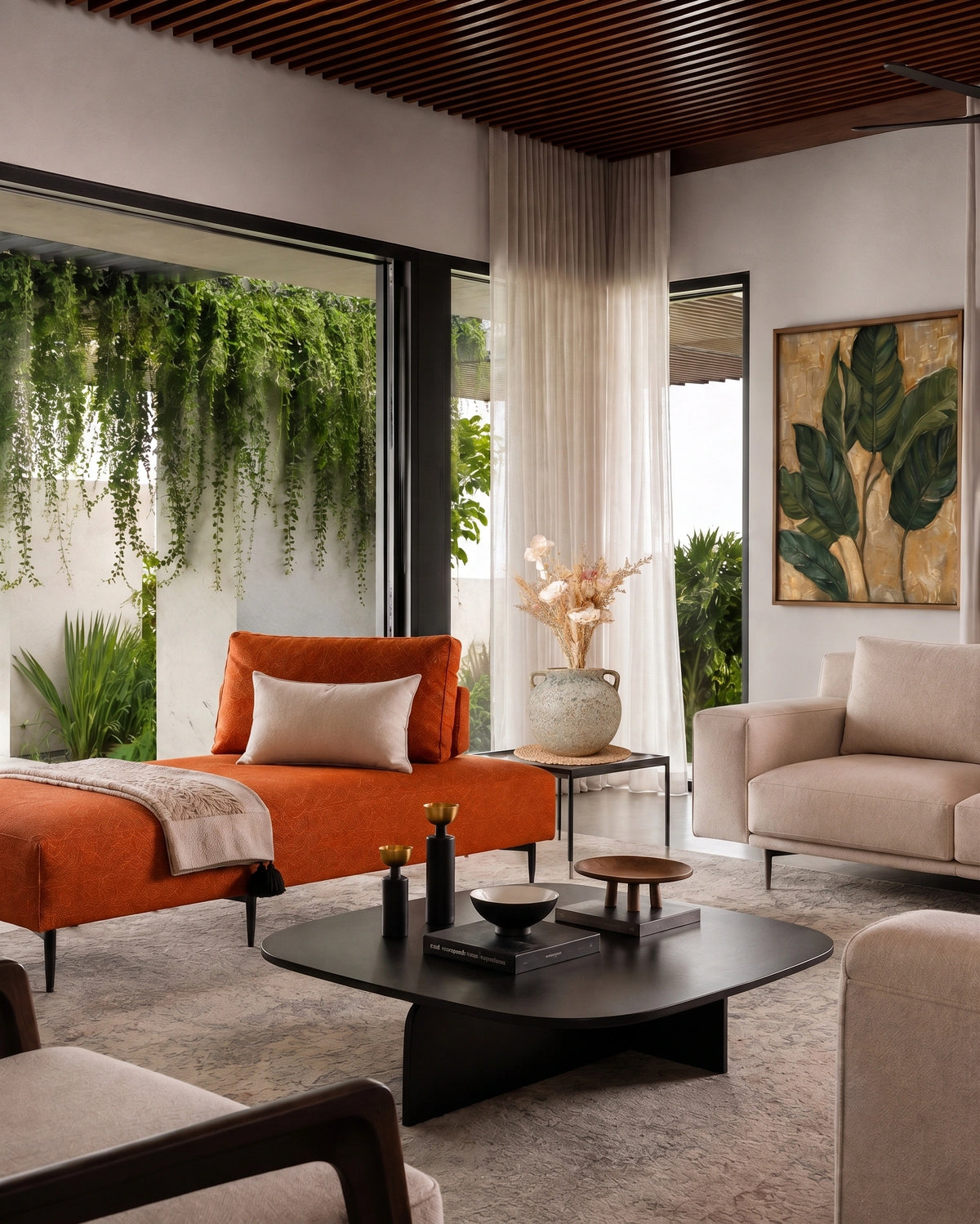 A modern living room interior featuring a bright orange chaise lounge with a cream pillow, a beige armchair, a black coffee table, and a large window showcasing hanging green plants.
