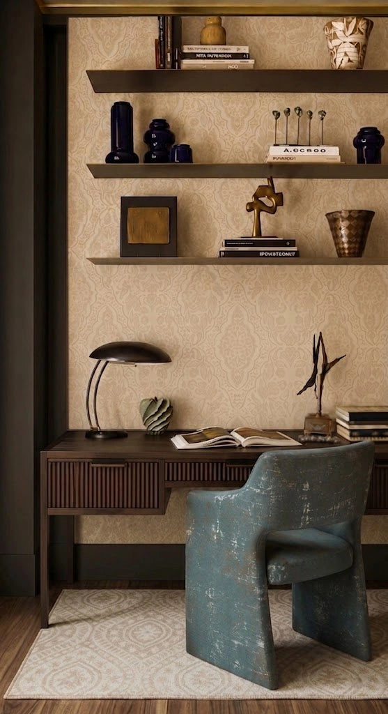 A styled home office corner featuring a dark wood desk, a distressed teal-green accent chair, and open shelving with decorative objects against a textured beige wallpaper background.